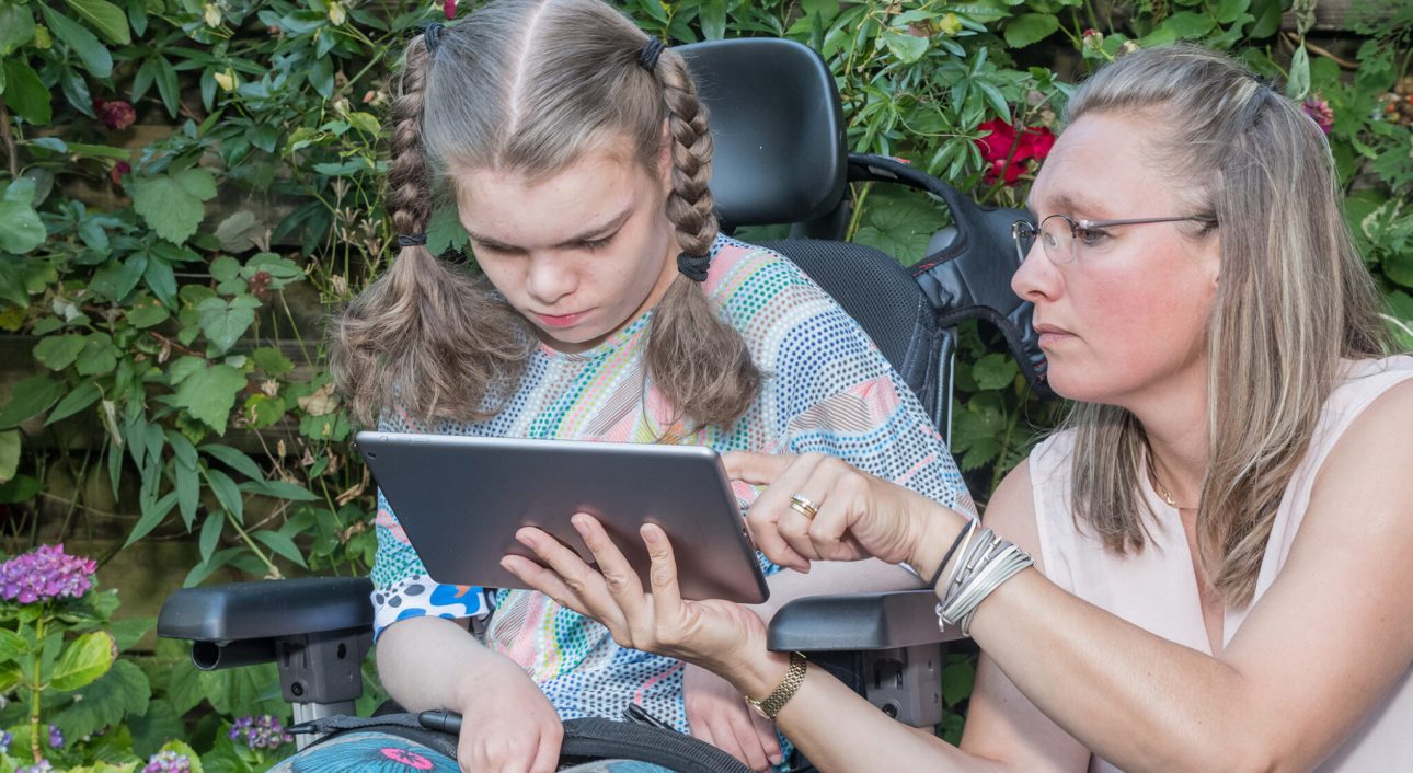 A disabled child learning and communicating with help from a special needs care assistant